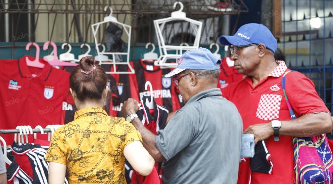 Sejumlah warga berebut membeli jersey  dan kaos tim Persipura di Kawasan Taman Imbi, Jayapura, Jumat (29/4/2016). (Bola.com/Nicklas Hanoatubun)