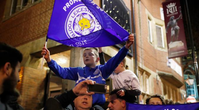 Seorang anak mengibarkan bendera Leicester City saat merayakan timnya meraih juara Liga Inggris setelah saingan terdekatnya Tottenham Hotspur bermain imbang 2-2 dengan Chelsea di sebuah pub di Leicester,(3/5).  (Reuters/Eddie Keogh)