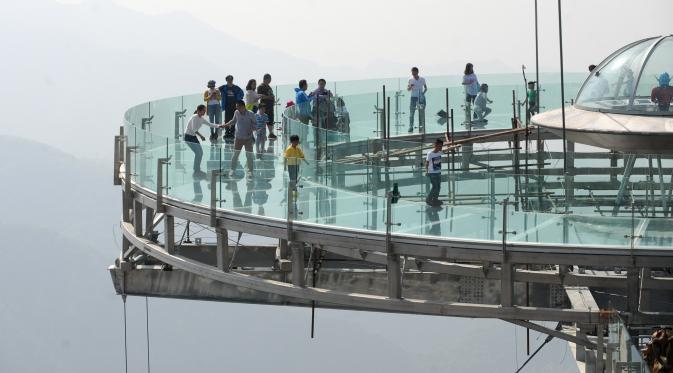 Sejumlah pengunjung berada di Panggung berlantai kaca udara yang berada di pinggir tebing di Shilinxia, Beijing, 30 april 2016. Panggung kaca yang menggantung hingga 32.8 meter dari tepi tebing ini merupakan objek wisata baru di China. (AFP PHOTO/STR)