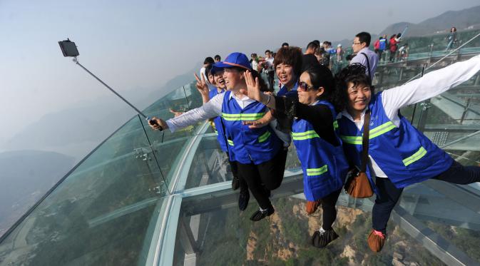 Pengunjung berfoto bersama di atas panggung berlantai kaca yang berada di pinggir tebing di Shilinxia, Beijing, 30 april 2016. Panggung kaca yang menggantung hingga 32.8 meter dari tepi tebing ini merupakan objek wisata baru di China. (AFP PHOTO/STR)