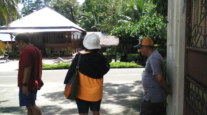 Seorang penjaga rumah Ahok (kanan) berbincang dengan wisatawan.