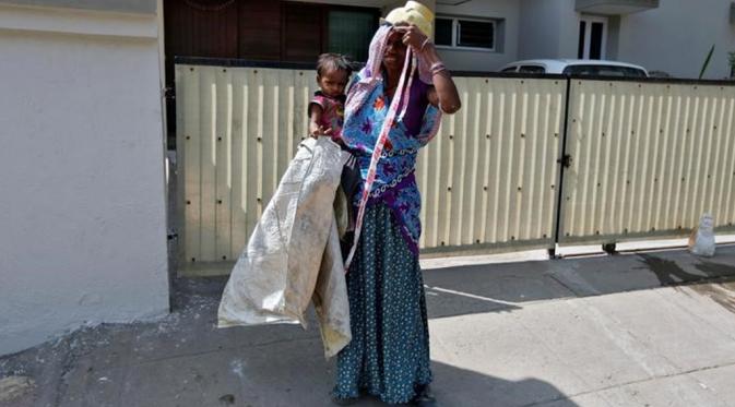 Sambil menutupi wajahnya dengan kain sari, Kalara mengatakan dia tidak punya pilihan selain megikat anaknya saat ia bekerja (Reuters).