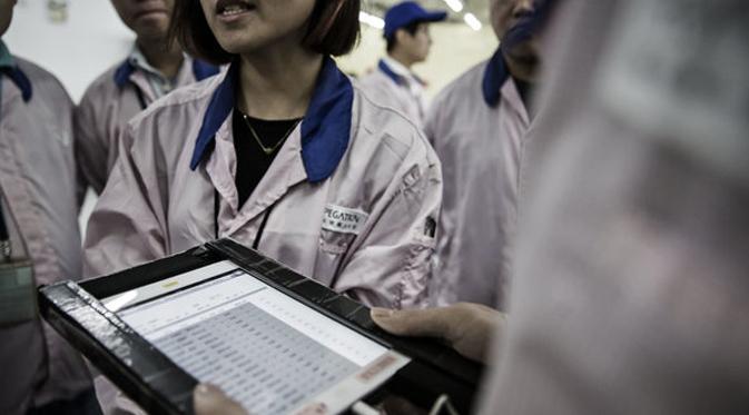 Seorang supervisor di fasilitas Pegatron memegang iPad. (Bloomberg)