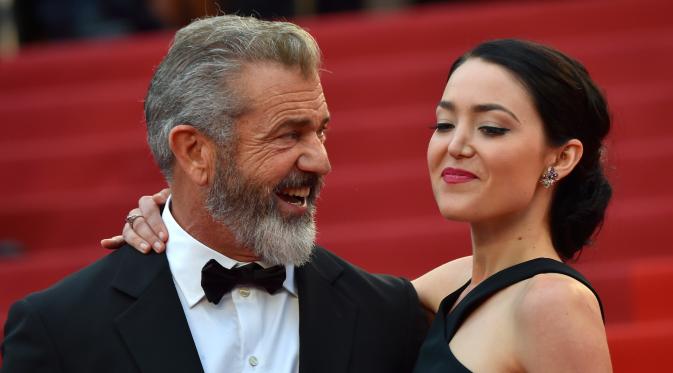 Aktor senior Mel Gibson tampak menatap sang kekasih, Rosalind Ross saat berpose di acara penutupan Festival Film Cannes, Prancis, 22 Mei 2016.  Seperti yang diketahui, usia Mel Gibson dan kekasih cantiknya terpaut 35 tahun. (A LOIC VENANCE/AFP)