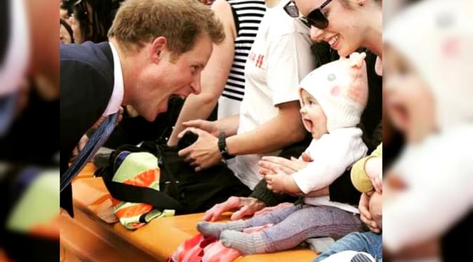 Pangeran Harry tengah bersenda gurau dengan anak kecil.