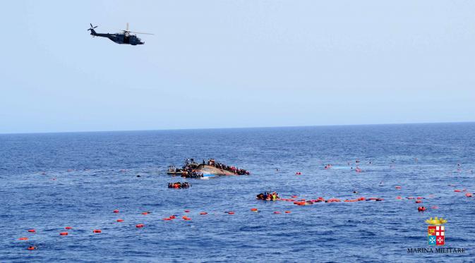 Helikopter berusaha mendekati sebuah perahu yang berisi para migran setelah terbalik di lepas pantai Libya, Rabu (25/5). Tujuh orang tewas tenggelam, sementara 500 orang lainnya berhasil diselamatkan dalam insiden tersebut. (STR/AFP MARINA MILITARE/AFP)