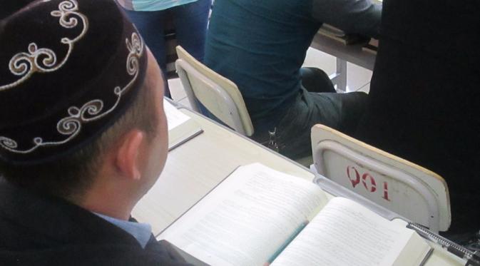 Berkostum baju koko dan peci khas Uighur, China, para siswa duduk rapi di dalam kelas. Membaca buku hadis Al Bukhari Muslim Aksara. (Liputan6.com/Arie Mega Prastiwi)