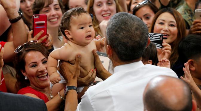 Presiden AS Barack Obama memegang bayi selama kunjungannya di Stasiun Udara Korps Marinir Iwakuni, Jepang (27/5). Kedatangan Obama ke Jepang untuk mennghadiri pertemuan G7. (REUTERS/Carlos Barria)