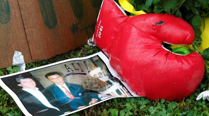 Sebuah foto dan sarung tinju diletakkan di rumah masa kecil Muhammad Ali untuk memberi penghormatan terakhir bagi petinju legendaris tersebut, di Louisville, Kentucky, AS, Sabtu (4/6). Muhammad Ali meninggal pada usai 74 tahun. (REUTERS/John Sommers II)