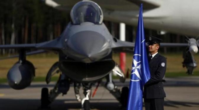 Tentara Polandia memegan bendara NATO di depan Jet F-16 (Reuters)
