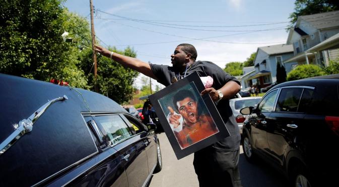 Seorang lelaki melemparkan bunga ke atas mobil jenazah Muhammad Ali. (Carlos Barria/Reuters)