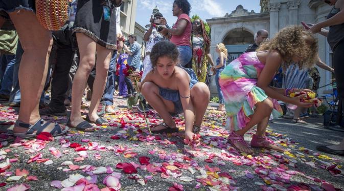 Anak-anak terlihat mengumpulkan bunga selepas mobil jenazah Muhammad Ali berlalu. (John Minchillo/AP)
