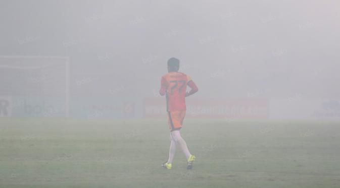 Kiper  Madura United, Hery Prasetyo menembus kumpulan asap dari flare  saat melawan Persiba Balikpapan pada laga Torabika SC2016 di Stadion Gelora Bangkalan, Senin(13/6/2016).  (Bola.com/Nicklas Hanoatubun)