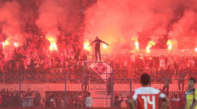Suporter Madura United, menyalakan flare memperingati ulang tahunnya membuat laga melawanRPersiba Balikpapan tertunda pada Torabika SC2016 di Stadion Gelora Bangkalan, Senin(13/6/2016).  (Bola.com/Nicklas Hanoatubun)