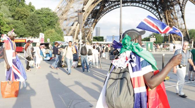 Pedagang menjajakan bendera-bendara peserta Piala Eropa 2016 di sekitar Menara Eiffel, Paris, Prancis, Jumat (23/6/2016) atau dini hari WIB. (Bola.com/Vitalis Yogi Trisna).