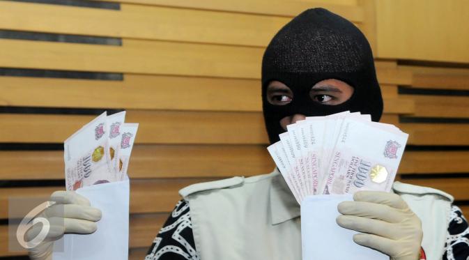 Petugas memperlihatkan barang bukti dalam OTT yang dilakukan KPK terhadap Panitera Pengganti Pengadilan Negeri Jakarta Pusat dengan mengamankan barang bukti uang sebesar 28.000 dolar Singapura, Jakarta, Jumat (1/7). (Liputan6.com/Helmi Afandi)
