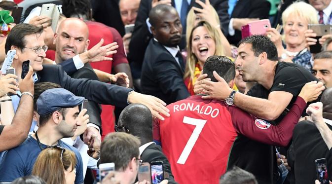 Striker Portugal, Cristiano Ronaldo, dipeluk seorang pendukung Portugal setelah meraih gelar juara Piala Eropa 2016 di Stade de France, Saint-Denis, Senin (11/7/2016) dini hari WIB. (AFP/Franck Fife)