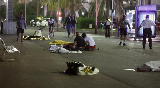 Sejumlah jasad korban serangan teror truk terbaring dengan tertutupi kain di jalanan Nice, Prancis, Kamis (14/7). Setidaknya 60 orang tewas saat sebuah truk menabrak kerumunan ramai yang merayakan libur nasional Bastille Day. (REUTERS/Eric Gaillard)