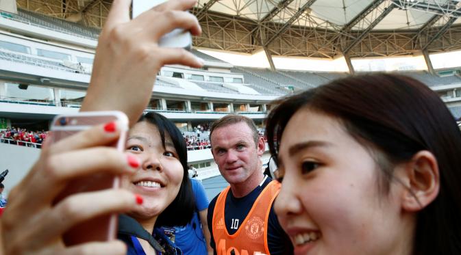 Kapten Manchester United Wayne Rooney menerima permintaan foto bareng di sela-sela tur Asia MU. REUTERS/Thomas Peter