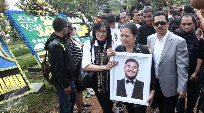 Ibunda Mike Mohede, Amin Yudhayani, memegang foto putranya dalam prosesi pemakaman di TPU Tanah Kusir, Jakarta, Selasa (2/8). Prosesi pemakaman Mike Mohede berjalan diiringi isak tangis keluarga, sahabat dan kekasihnya. (Liputan6.com/Herman Zakharia)