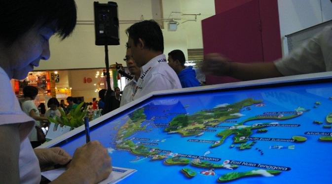 Seorang pengunjung pameran wisata MITM sedang mencari destinasi wisata Indonesia menggunakan peta interaktif. 