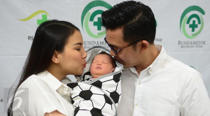 Pemain Sinetron Tya Ariestya dan suaminya Irfan mencium anak pertamanya di rumah sakit kasawan Cikini, Jakarta, Sabtu (6/8/2016). Anak pertama pasangan Tya dan Irfan diberi nama Muhammad Irfan Ratinggang.( Liputan6.com/Herman Zakharia)
