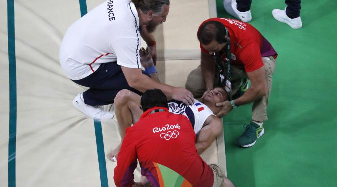 Atlet senam artistik Prancis Samir Ait Said mendapat penanganan dari tim medis usai cedera serius di kaki kirinya saat berlaga di Olimpiade Rio 2016.  (Thomas COEX / AFP)