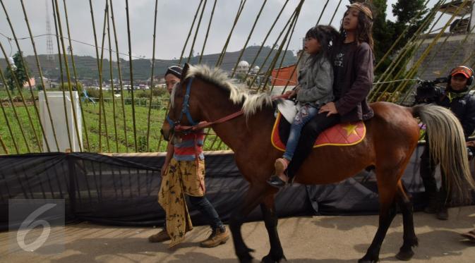 Anak berambut gimbal menaiki kuda saat acara ritual ruwatan potong rambut gimbal di komplek candi Arjuna dataran tinggi Dieng Desa Dieng Kulon, Jateng, Minggu (3/7).Prosesi adat ini akan memotong 11 anak berambut gimbal.(Gholib)