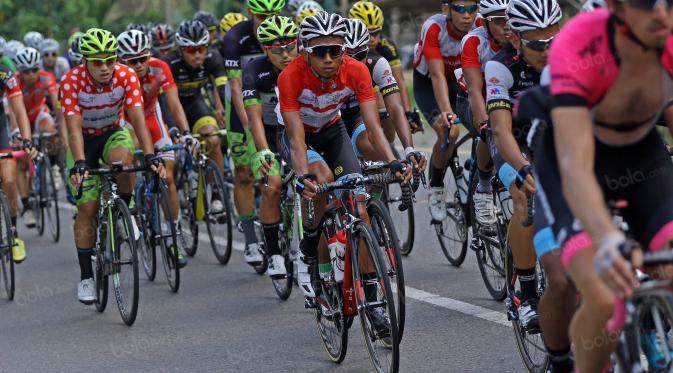 Pebalap Terengganu Cycling Team asal Indonesia, Dady Suryadi (merah putih) bersaing ketat dengan para pebalap dari Iran pada etape ke-7 dari Kabupaten Sijunjung Menuju Dharmasraya, Sumatera Barat, Jumat (12/8/2016).  (Bola.com/Nicklas Hanoatubun)