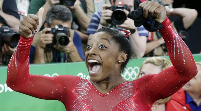 Simone Biles dari Amerika Serikat merayakan keberhasilannya meraih medali emas pada ajang artistic gymnastics Olimpiade Rio 2016 di Brasil, (14/8/2016). (AP/Dmitri Lovetsky)