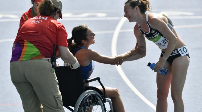 Abbey D'agostino menggunakan kursi roda karena nyeri pada kakinya setelah terjatuh dan dibantu pelari Selandia Baru, Nikki Hamblin (kanan), pada lari 5000m putri Olimpiade Rio 2016 di Olympic Stadium, Rio de Janeiro, (16/8/2016). (AP/Martin Meissner)