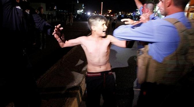Bocah yang didiuga berusia 12 hingga 13 tahun itu menangis saat polisi Irak melucuti bom yang berada di tubuhnya (Reuters)