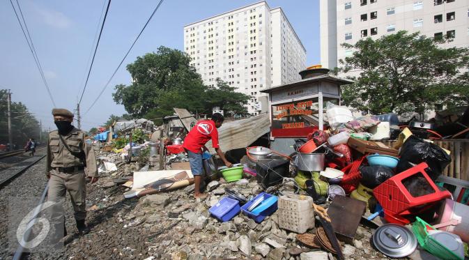 Warga merapihkan barang miliknya saat alat berat merobohkan bangunan di kawasam Rawajati, Jakarta, Kamis (1/9). Penertiban tersebut menyebabkan warga terpaksa menyelamatkan barang berharga mereka ke tepi rel kereta api. (Liputan6.com/Immanuel Antonius)