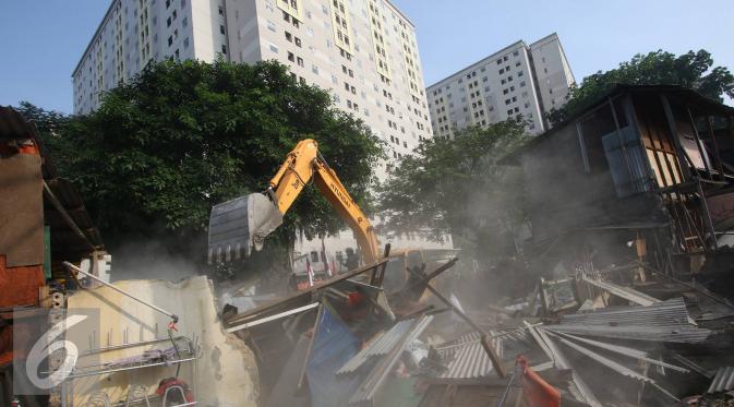 Alat berat merobohkan bangunan di kawasam Rawajati, Jakarta, Kamis (1/9). Penertiban puluhan bangunan liar di kawasan tersebut menyebabkan warga terpaksa menyelamatkan barang berharga mereka ke tepi rel kereta api. (Liputan6.com/Immanuel Antonius)