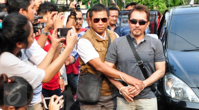 Ketua Umum Persatuan Artis Film Indonesia (PARFI) Gatot Brajamusti alias Aa Gatot dikawal petugas saat tiba di rumahnya di kawasan Pondok Pinang, Jakarta, Kamis (1/9). (Liputan6.com/Yoppy Renato)