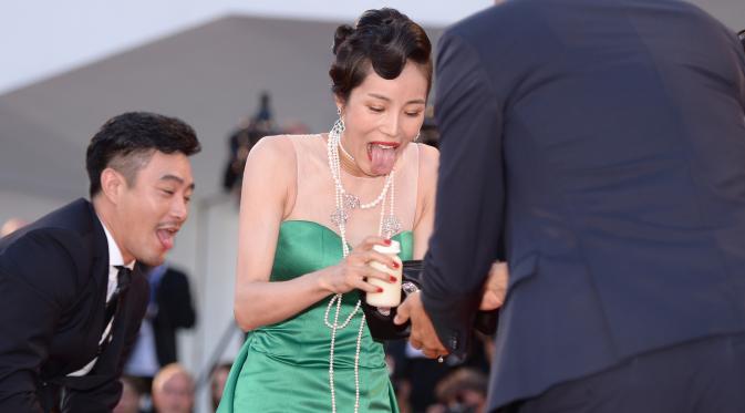 Ekspresi Aktris Korsel, Moon So-ri usai jatuh karena sepatu hak tingginya menginjak bagian bawah gaun yang panjang menjuntai di karpet merah pemutaran perdana film The Light Between Two Ocean di Venice Film Festival, Kamis (1/9). (FILIPPO MONTEFORTE/AFP)