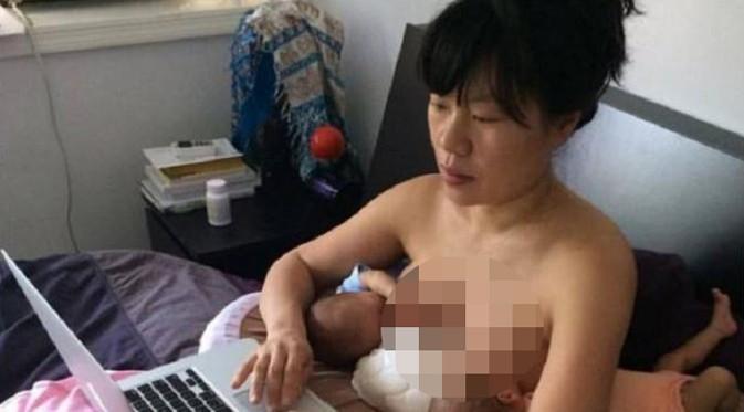 Seniman Hein Koh mengunggah sebuah foto dirinya tengah menyusui putri kembarnya sambil bekerja. (Foto: Metro)