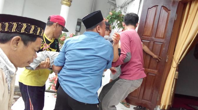 Warga menggotong Ustad Fuad yang pingsan usai menyembelih sapi sumbangan Jokowi. (Liputan6.com/Yuliardi Hardjo Putro)