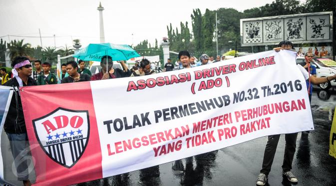 Massa Asosiasi Driver Online (ADO) membentangkan spanduk di depan Istana, Jakarta, Senin (19/9). Dalam aksinya, mereka menolak diberlakukan ujian kendaraan bermotor (KIR) menggunakan SIM A UMUM per 1 Oktober 2016. (Liputan6.com/Faizal Fanani)
