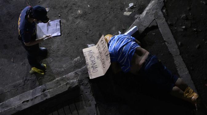 Seorang penyidik polisi berdiri di dekat tubuh pria yang diikat kepala dan kakinya di Manila, Filipina, (21/9). (REUTERS/Ezra Acayan)