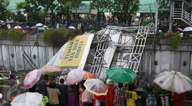 Warga menonton Jembatan Penyeberangan Orang (JPO) yang roboh akibat hujan deras dan angin kencang di Jalan Raya Pasar Minggu, Jakarta Selatan, Sabtu (24/09). Petugas masih memotong bagian JPO tersebut. (Liputan6.com/Immanuel Antonius)