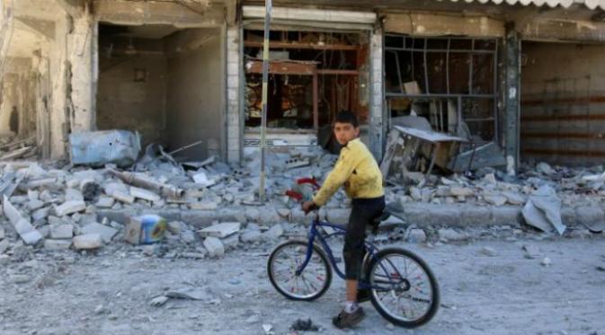 Seorang anak berada di depan toko yang hancur akibat serangan udara di Suriah (Reuters)
