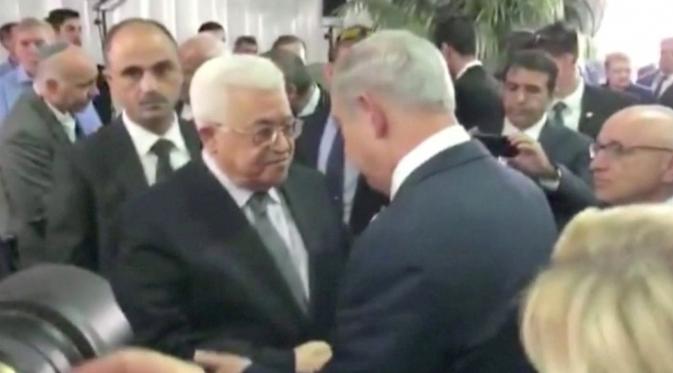 Presiden Palestina Mahmoud Abbas berjabat tangan dengan Perdana Menteri Israel Benjamin Netanyahu pada pemakaman mantan Presiden Israel Shimon Peres di Yerusalem, Jumat (30/9). Peres meninggal dunia karena terkena stroke di usia 93 tahun. (REUTERS)