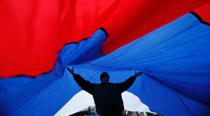 Seorang pria memegang bendera Rusia (Reuters)