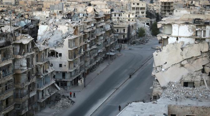 Sejumlah orang berjalan melewati bangunan yang hancur akibat pertempuran di Tariq al-Bab yang dikuasai pemberontak di Aleppo, Suriah, (5/10). PBB memperkirakan 275.000 orang terperangkap dalam pertempuran tersebut. (REUTERS/Abdalrhman Ismail)