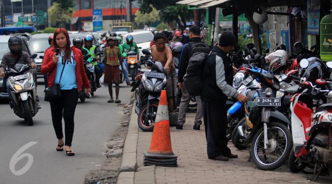 Warga melintas di samping trotoar yang dijadikan tempat parkir motor di Jalan Juanda, Bekasi, 4 Oktober 2016. Trotoar yang seharusnya untuk pejalan kaki ini dialih fungsikan oleh jasa parkir liar sebagai tempat parkir kendaraan bermotor. (Foto: Fajar)