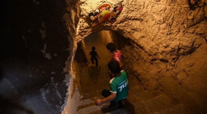 Anak-anak berjalan melalui sebuah terowongan yang menghubungkan dua ruangan dari sebuah taman hiburan di bawah tanah di Harbin, luar Damaskus, Suriah. (foto: Mohammed Badra)