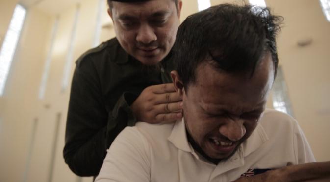 Seorang pasien rukyah meringis saat Ustaz Adam Amrullah mengusir jin dari tubuhnya (Liputan6.com/Mochamad Khadafi)