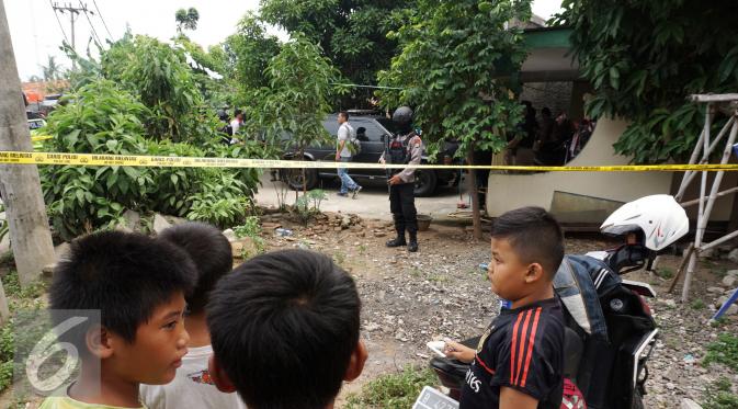 Anggota polisi bersenjata lengkap bersiaga di depan rumah orangtua SA, pelaku penusukan tiga anggota polisi, di Kelurahan Sepatan, Tangerang, Kamis (20/10). Sebelumnya SA menyerang Pospol Cikokol dan melukai tiga anggota polisi. (Liputan6.com/Stringer)