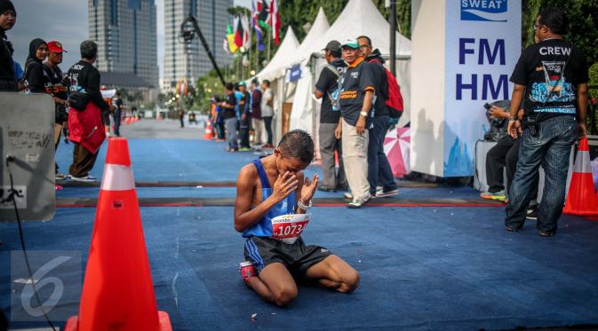 Salah satu peserta kategori full marathon berdoa usai mencapai garis finish saat Mandiri Jakarta Marathon 2016 di Monas, Jakarta, Minggu (23/10). Dari 16.000 peserta, ada 2.500 orang yang mengikuti lomba kategori full maraton. (Liputan6.com/Faizal Fanani)